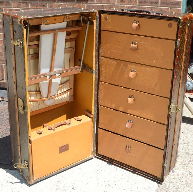 Antique Louis Vuitton monogram wardrobe circa 1910 in excellent antique condition and previously owned by Liberace.  Monogram canvas exterior trimmed with wood paneling, leather, and bronze hardware.  Orange canvas interior with 6 storage drawers,