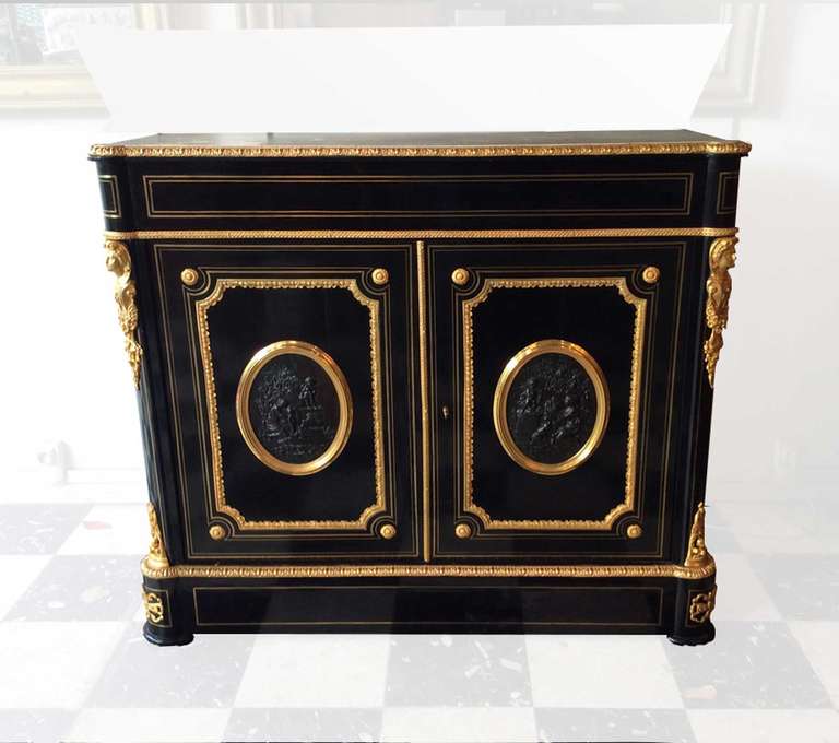 Pretty Napoleon III cabinet, ebony veneer on a core of solid oak. The interior is clad in varnished mahogany. Rich ornaments of gilded bronze. The two doors are decorated with medallions in patinated bronze, each medallion is different.
The