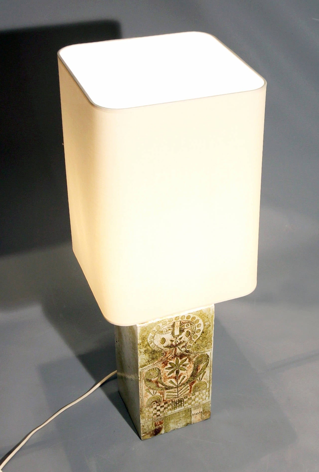 Square earthenware lamp with incised figural decoration and enameled rough ceramic texture. Signed on back 