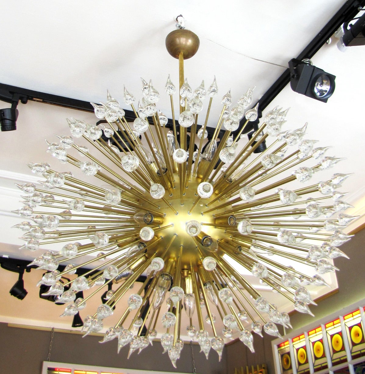 Large chandelier, all in polished brass; the rods are terminated by pretty drops glass with bubbles, that reflect and magnify the light of the small bulbs. Italy circa 1980.