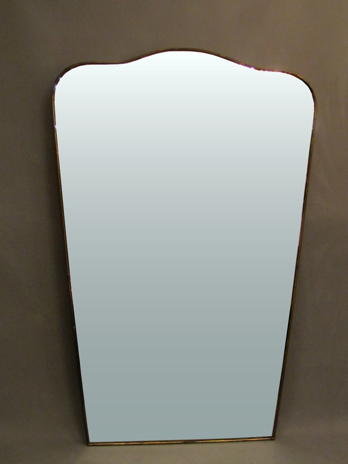 Large 1950s Italian mirror with brass frame, shaped as escutcheon.
The lower width of mirror is 23.62 in.