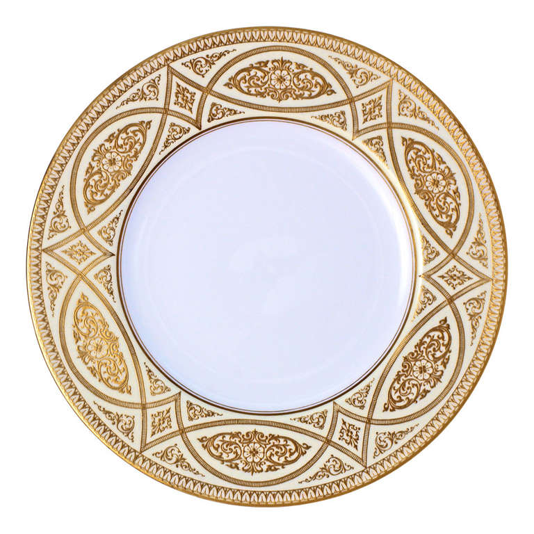 These Art Deco dinner plates have an elegant style. Made in 1923 for Marshal Field & Company, they mix classical elements for a lush detailed look. The center ground is white and the rim is a soft yellow cream. The hand gilded decorations are