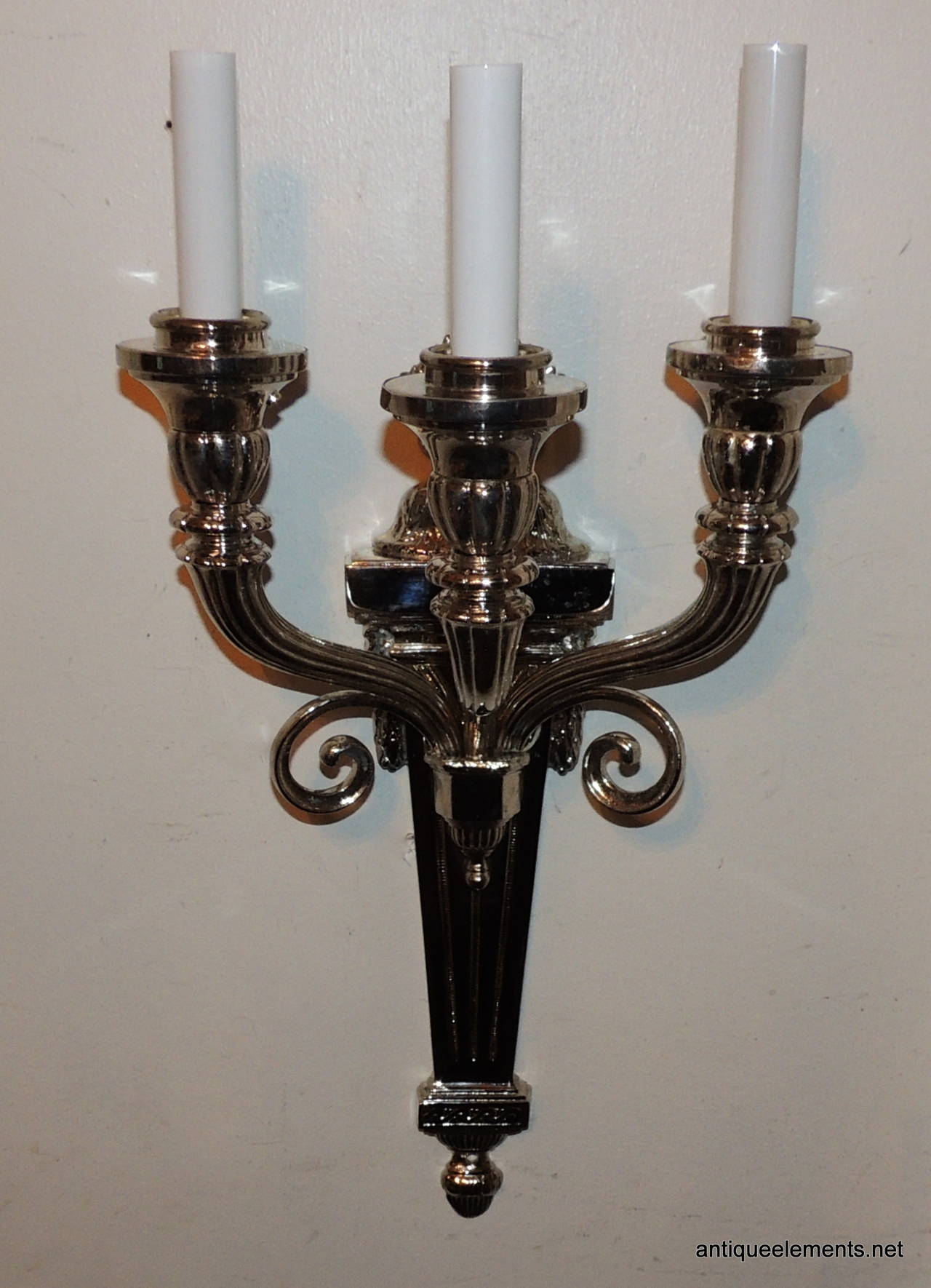 This elegant pair of neoclassical nickel-plated sconces are attributed to Caldwell. Very neoclassical in design with the linier detail through the centre and on the bobeches, the flame top and highlighted with the beautiful scroll detail. The