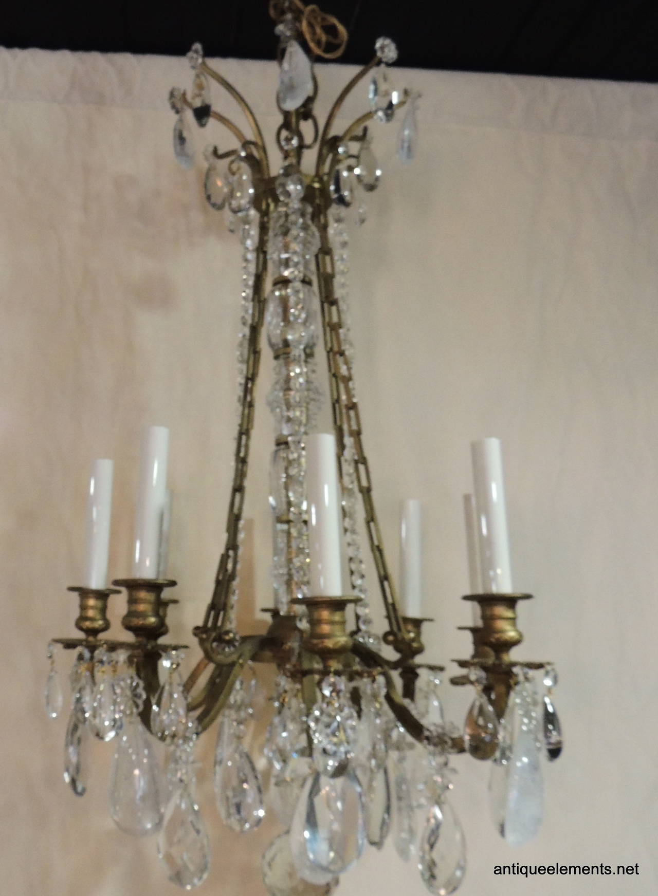 A wonderful gently aged French bronze chandelier with eight arms, center crystal chains and crystal crown finished with both rock and cut crystal pendants. The center is adorned with variated crystal columns.

Measures: 17