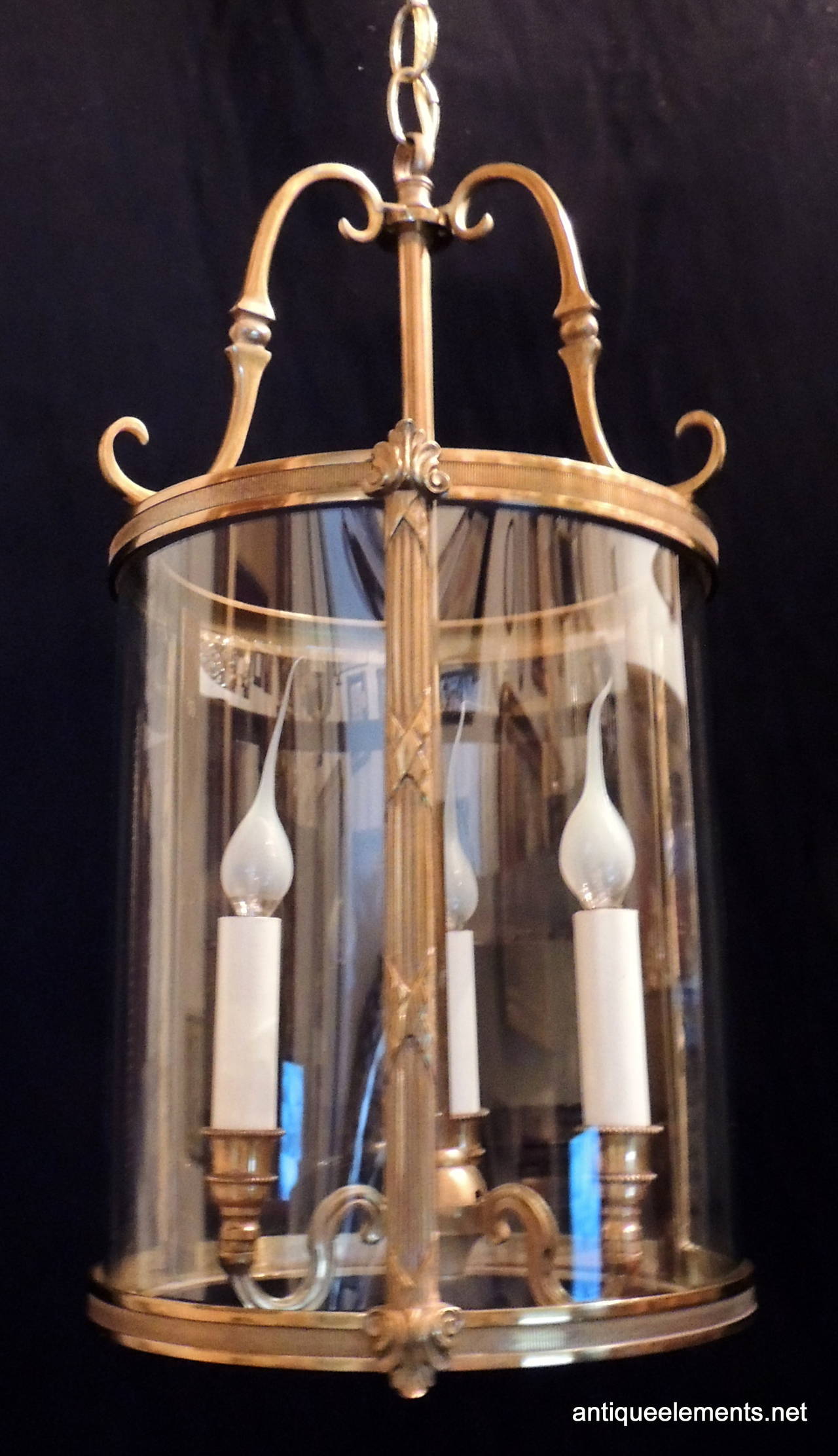Perfect for a hallway or a covered porch, this classic pair of dore bronze and curved glass 3 light lanterns. With beautiful scrolls curving at the top and supporting the lights, and beautiful etching around the bronze edges  and supports of the