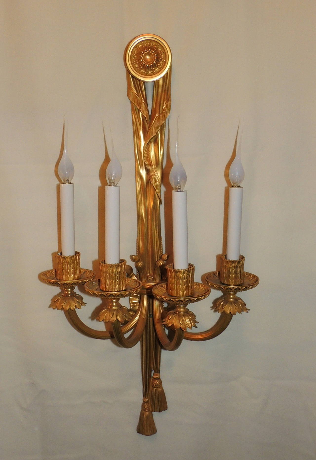 These beautiful doré bronze sconces are truly breathtaking. They are full of incredible detail, beginning from the long ribbon leading down to the beautiful bow in the center, to each intricate arm finishing at the tassel bottom. They have been