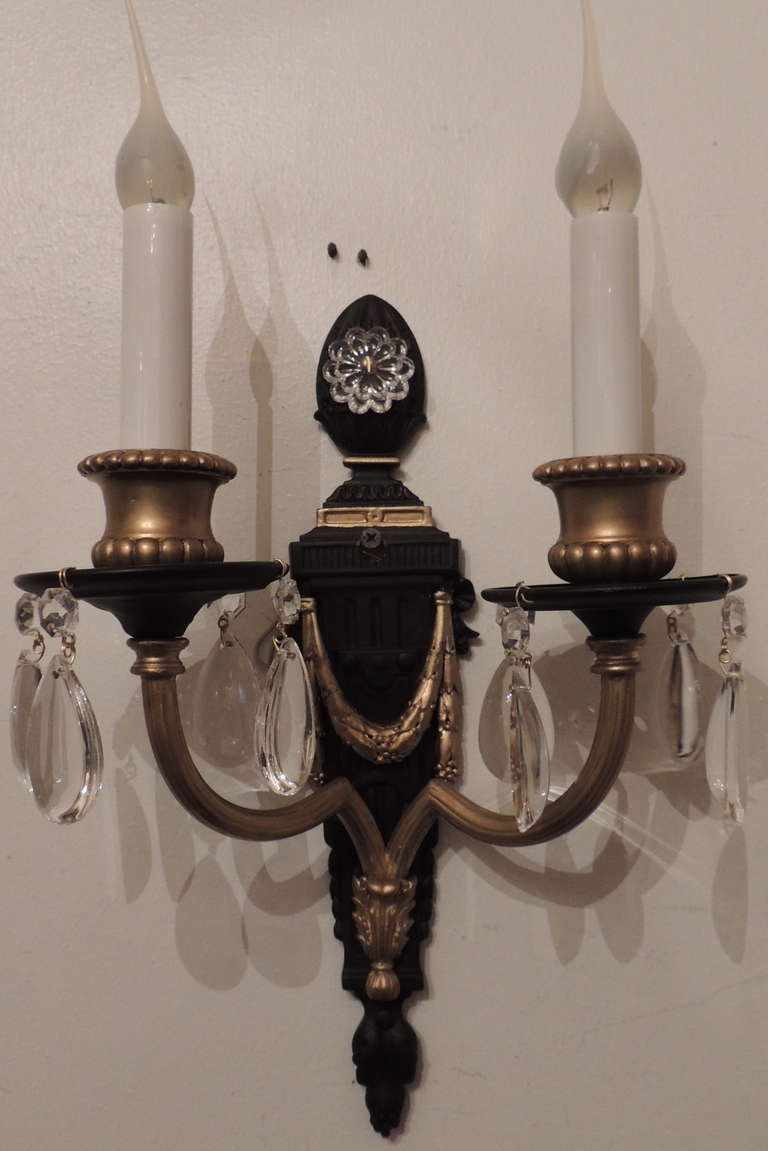 A fine pair of patina and gilt bronze neoclassical
two-arm wall sconces in urn form with swag
centrepiece adorned with crystals.

By E. F. Caldwell & Co.