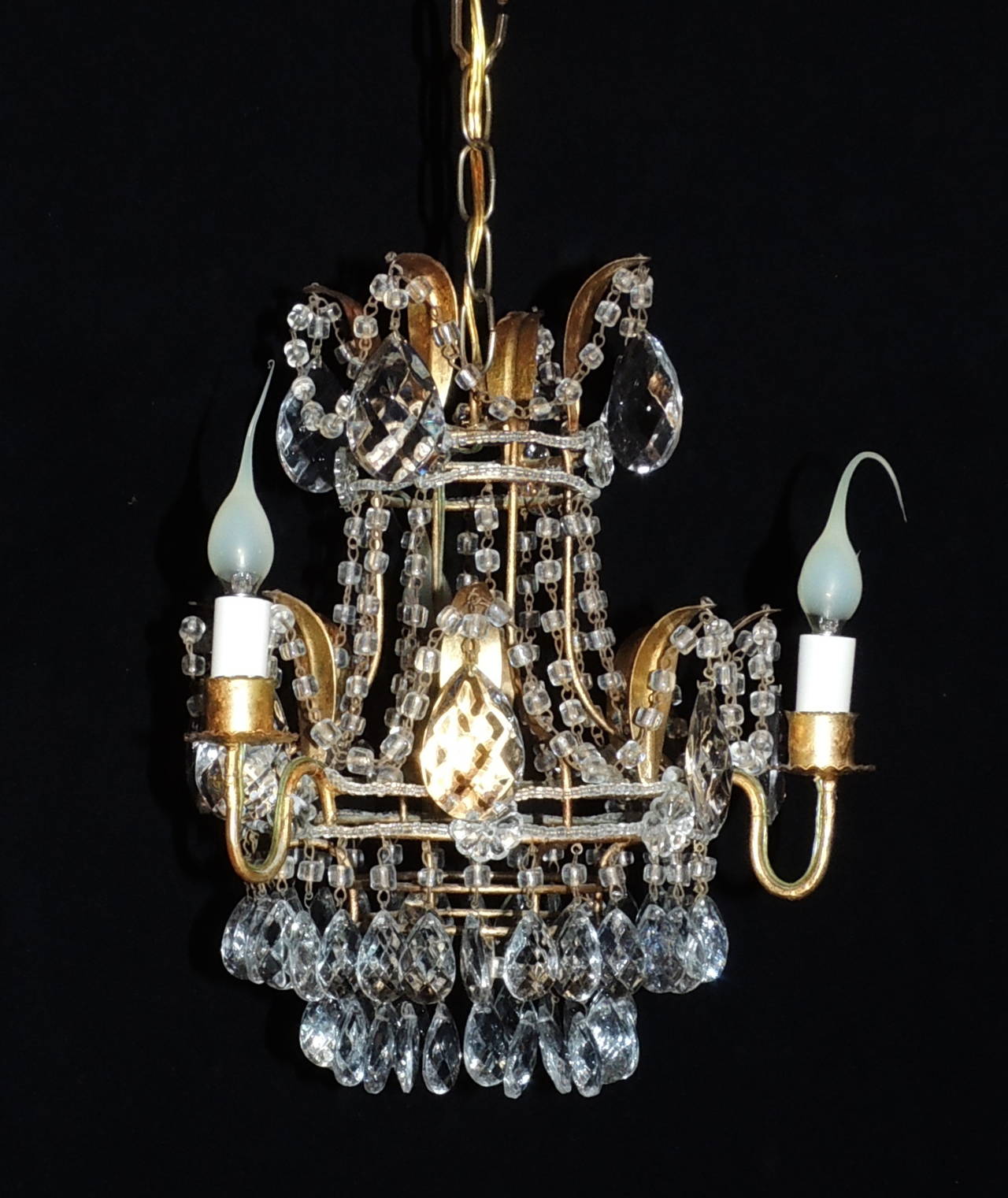 Full of crystal, this petite Gilt 3 arm chandelier is sure to be a perfect addition to that small niche, room, hallway or bath. Prism drops, crystal draping, sweeping bronze leaves, molded scalloped bronze bobeches and finished with 2 rows of