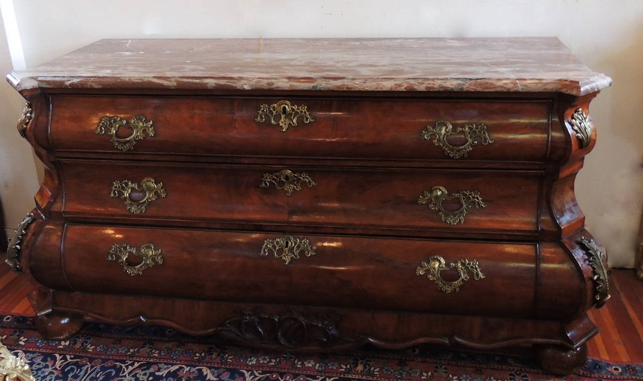 This full length mahogany sideboard from the early 1900s with three large divided drawers is detailed with beautiful bronze-mounted scroll and leaf designs at the two corners and on the drawers. The shaped molded edge marble top has shades of rose,