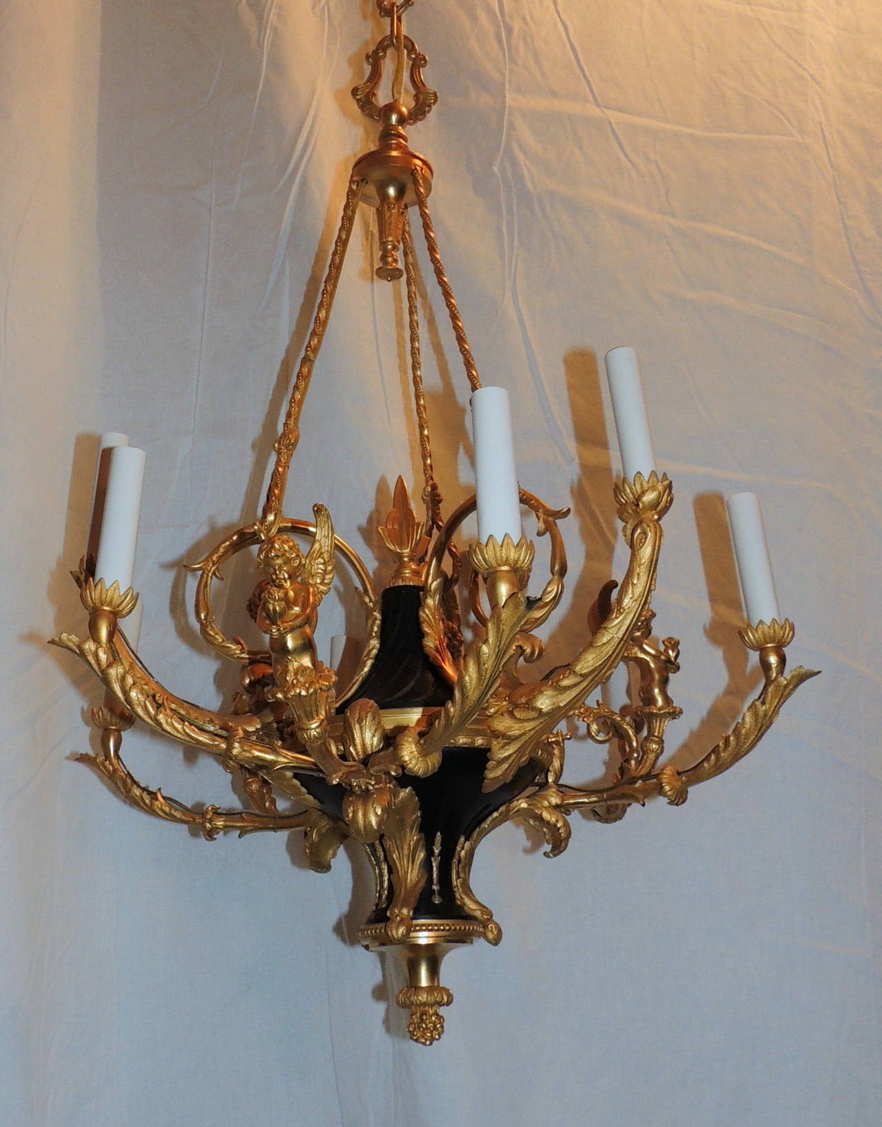 A wonderful 19 century French Dore Bronze chandelier with black carved marble center and beautiful gilt bronze scroll arms supporting the 3 winged cherubs holding a flower surrounded by 3 lights. The 9 lights allow this chandelier to produce light 