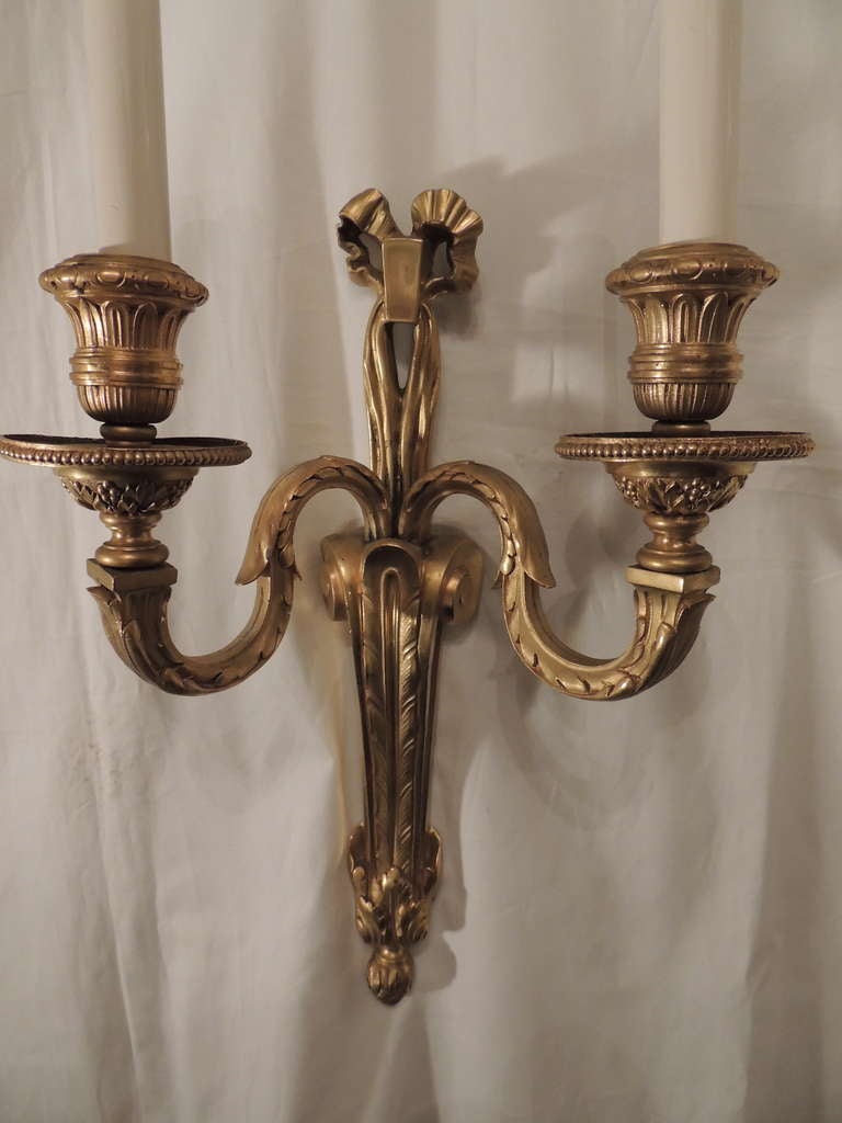 Set of four French doré bronze bow top two-light wall sconces in the style of Caldwell.