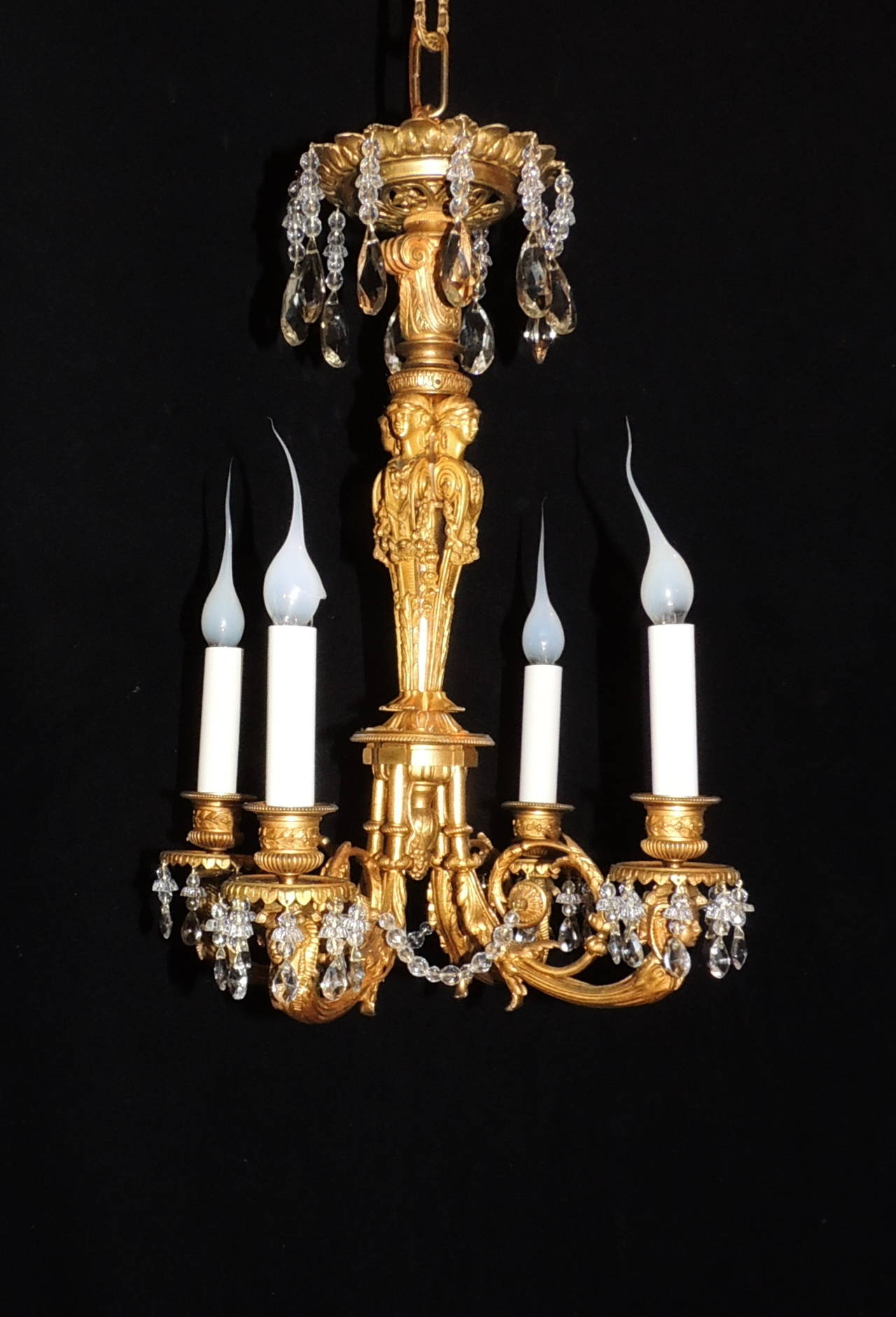 Medusa looks down from the top of this four-light doré bronze and crystal chandelier. Surrounding the center are four standing female figures elaborately detailed with scroll and floral de´cor. The four arms are decorated with etched scrolls,