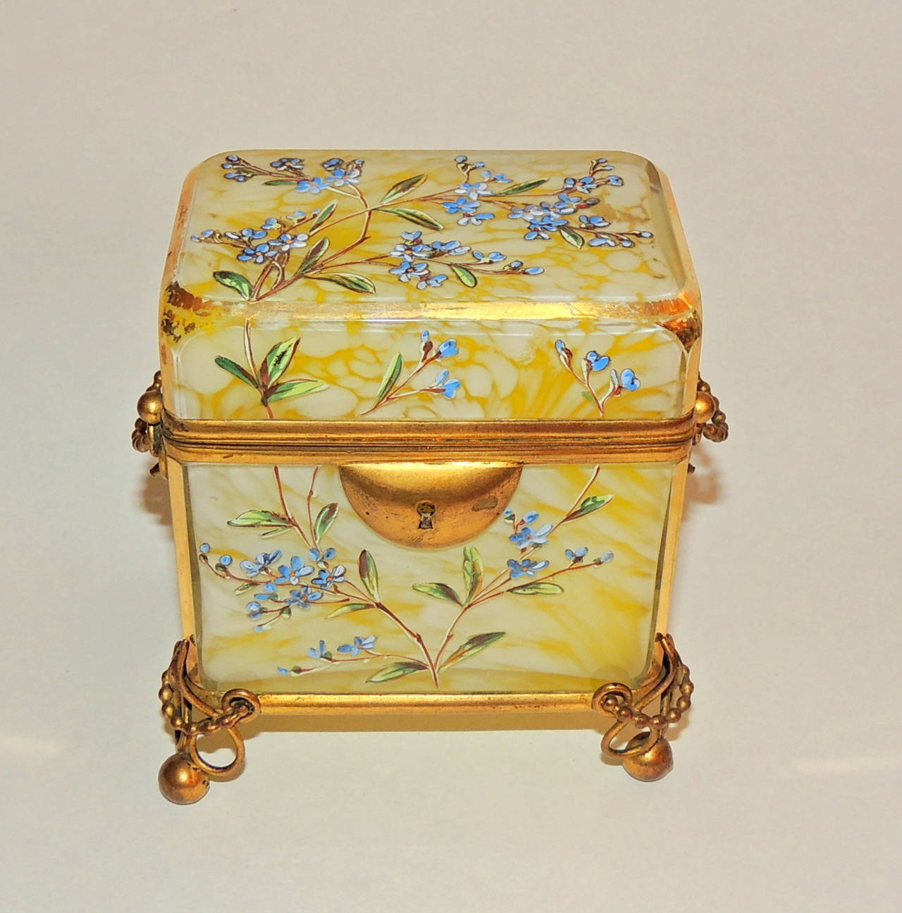 A wonderful and unusual marbleized yellow and white crystal casket with delicate hand painted enamel floral designs in blues and greens.  Beautiful and intricate scroll ormolu mountings decorate the balled feet and pretty handles of the casket.  The