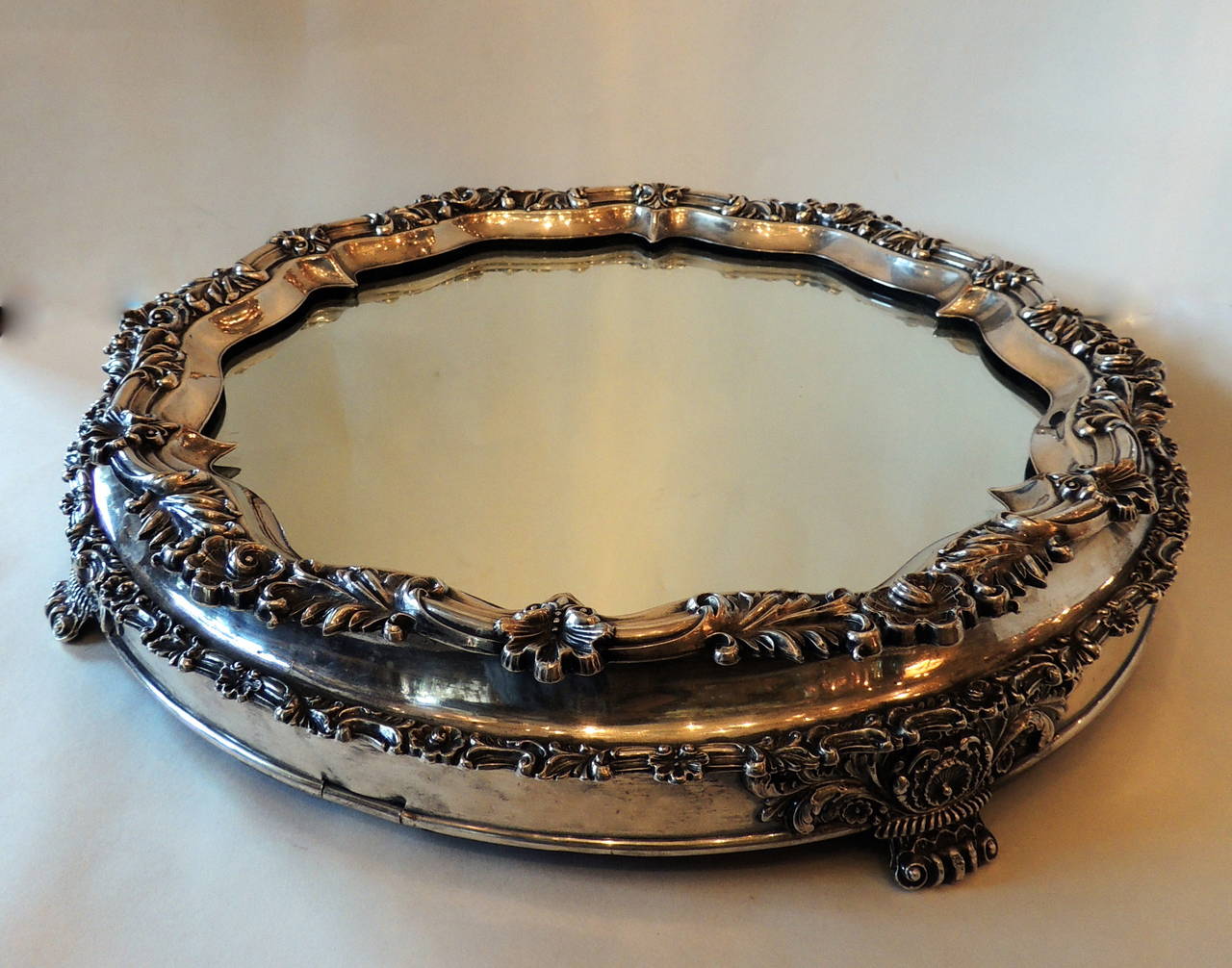Wonderful 19th century silver plate plateau has a rich floral embellishment with circular mirror. The beautiful patina adds to the look of this antique plateau.
Original numbered feet and attachments are on the bottom. 

Measures: 17