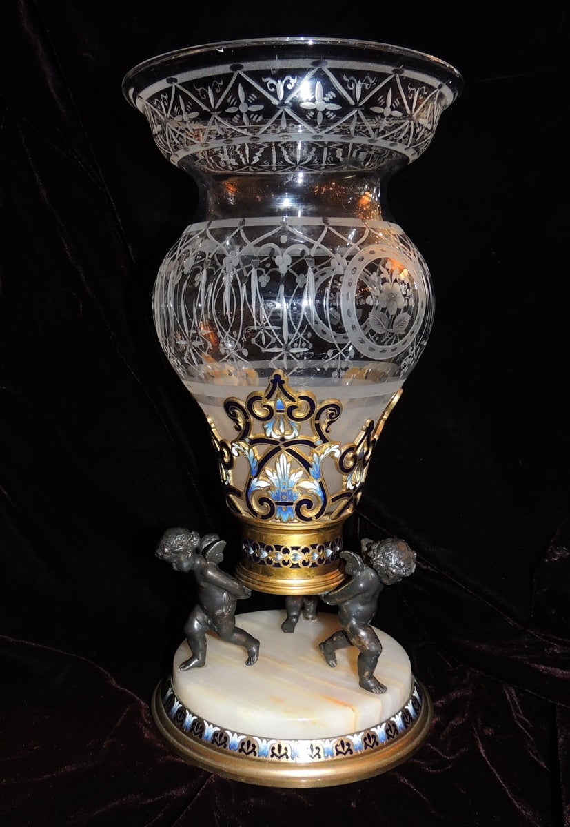 Incredible 19th century etched crystal centrepiece has three enchanting patinated cherubs standing on an onyx base. The doré bronze on the center and on the base are beautifully decorated with beautiful blue enamel. 
The etching on the crystal is