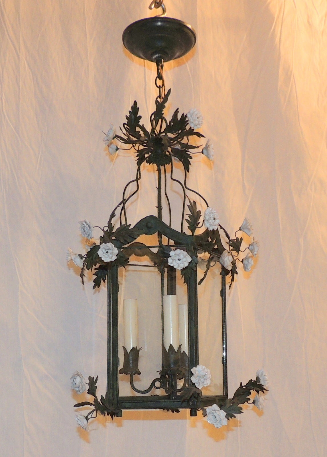 An enchanting green metal lantern with wonderful green leaf detail and delicate white porcelain flowers with three lights. Perfect as a hallway or covered porch chandelier or to have an unusual piece in your home.

24