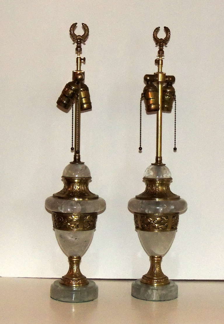 A Very Handsome Pair Of Thick Rock Crystal Lamps In Urn Form Shape With Engraved Bronze Details. Each Lamp Has Two Lights. The Center Urn Portion Is 5 1/2 Inches At The Widest Point, On A 4 1/2 