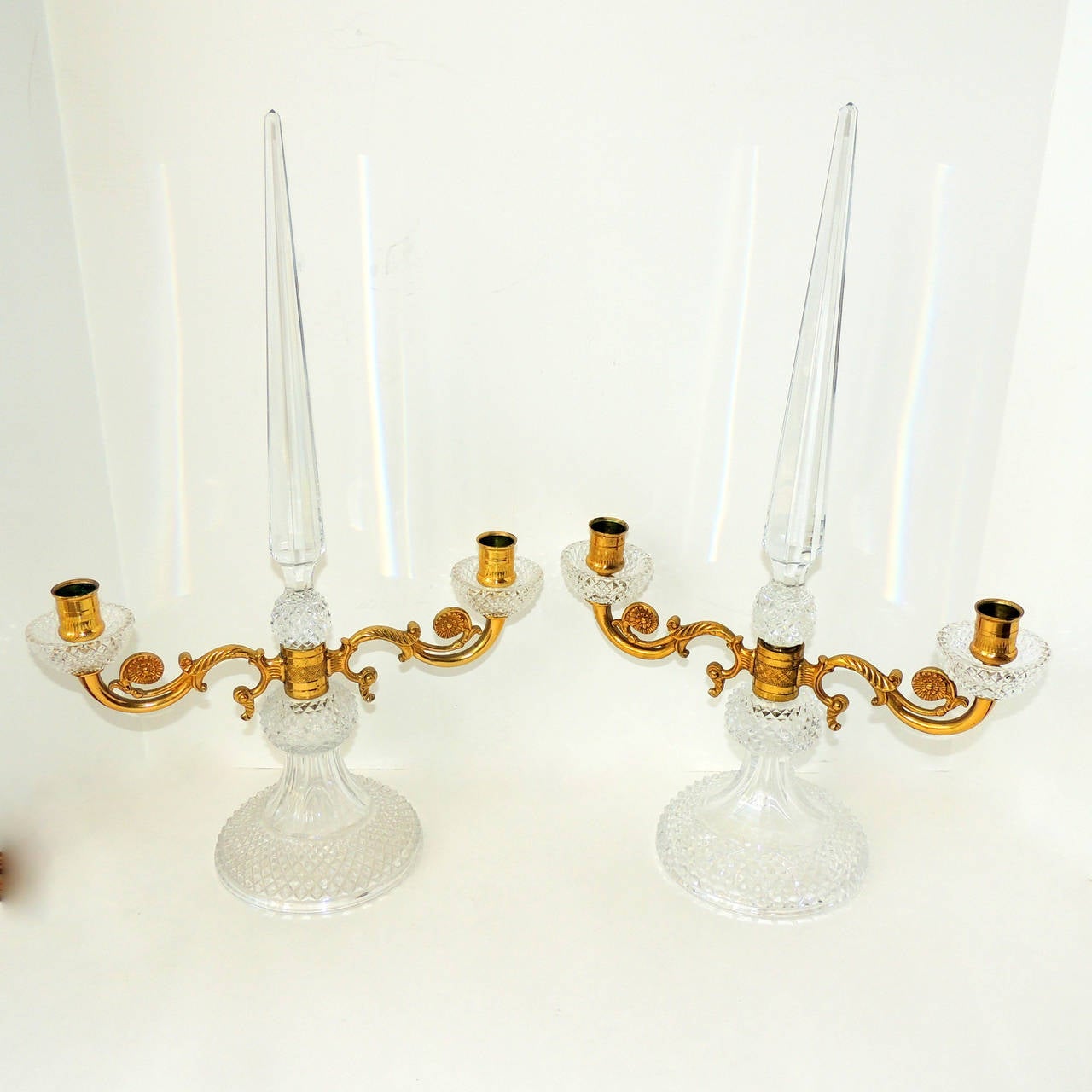 Ces élégants candélabres sont dotés d'une magnifique flèche au centre et d'un magnifique cristal taillé qui scintille à la lumière des bougies. Le centre en bronze doré est décoré de façon complexe avec des volutes qui accentuent les bras. 
Dans le