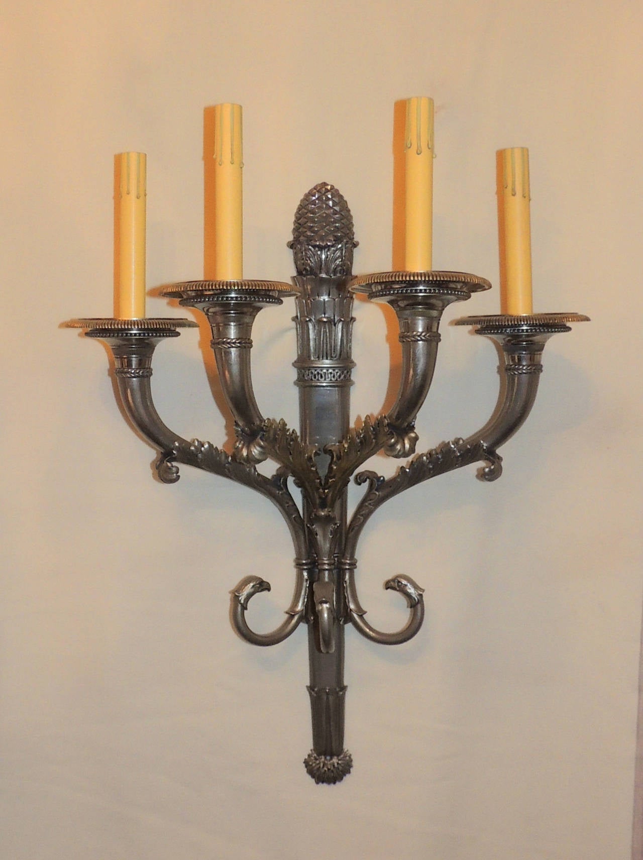 This pair of neoclassical four-arm sconces are beautifully aged silvered bronze with a very wonderful rich patina. Decorating the four arms are beaded trim and floral scrolls embracing the arms. The center of the sconces are detailed with raised