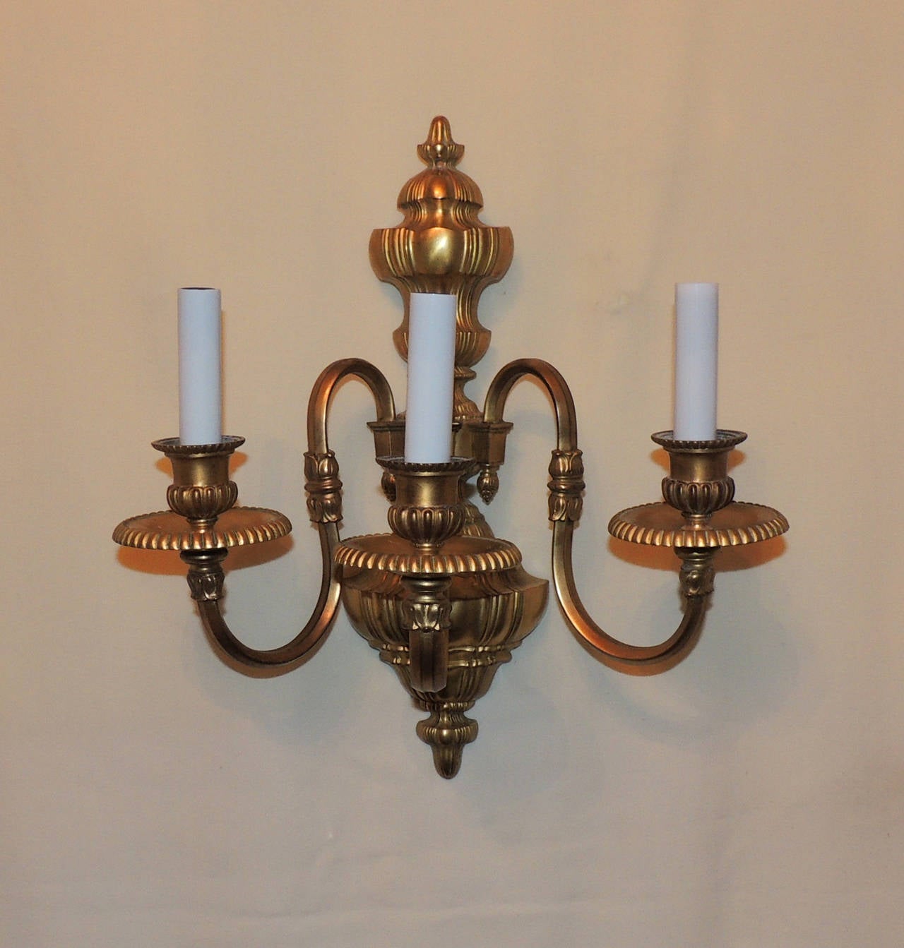 Wonderful fluted detail work encompass these Caldwell doré´ bronze sconces in the Georgian style. The centre urn is 16" high with three arms on sweeping curved arms and are 8" in depth. Wonderful aged patina will look wonderful in many