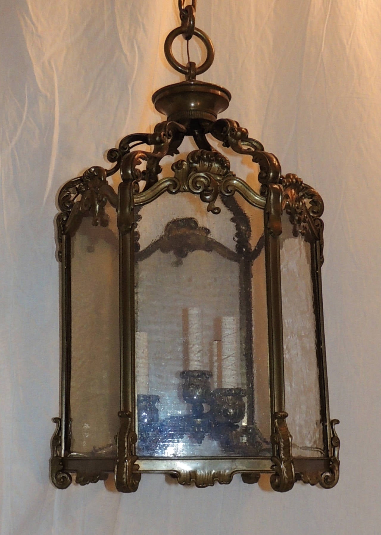 This wonderful bronze lantern by Caldwell has four lights and the original glass. Each of the hexagon sides is topped with beautiful bronze scroll design that continues at the top and on the base. The bobeches are beautifully designed with the