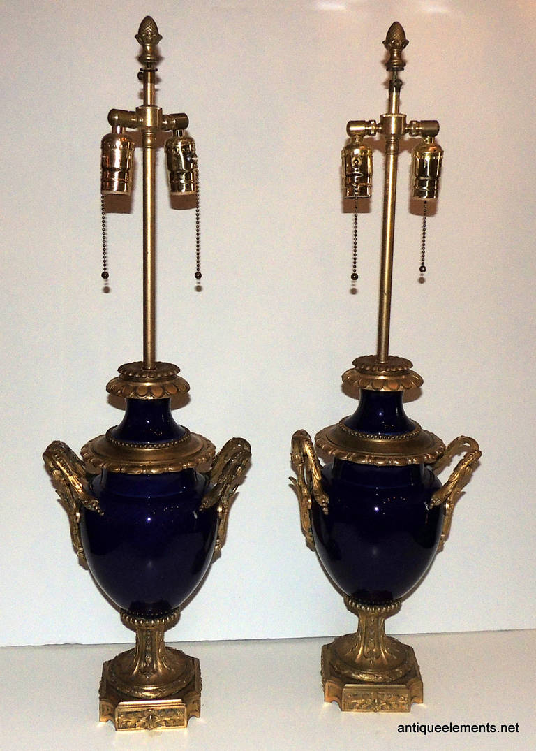 French elegance is what you will find in this beautiful 19th century Cobalt Blue set of Sevres urn style lamps with double lights. The dore bronze mounts and handles are exquisitely detailed with floral and scroll elements which are beautifully aged