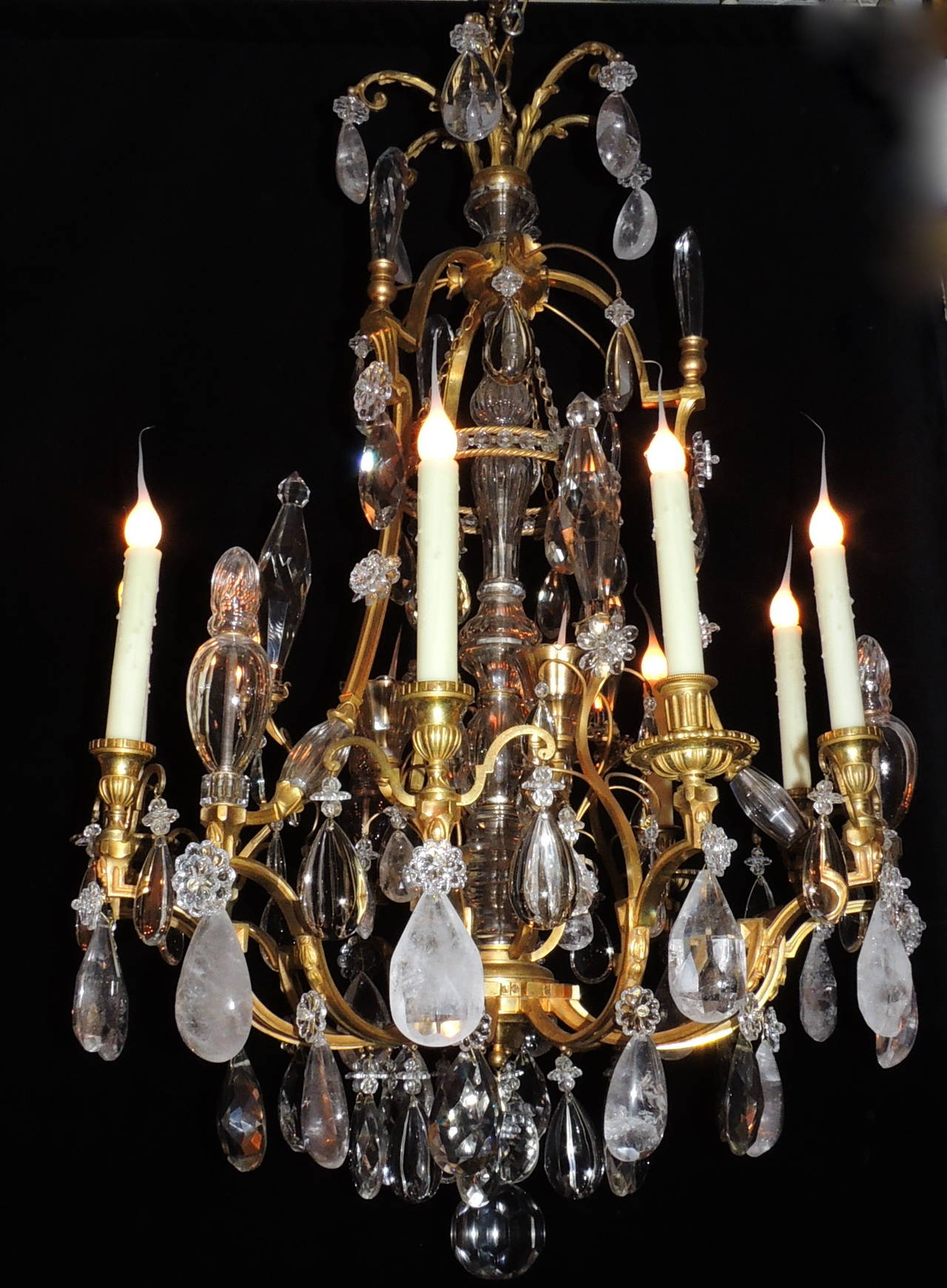 This wonderful twelve-light doré bronze rock crystal and crystal chandelier has beautiful large rock crystal drops accented by crystal flowers and elegant cut crystal prisms which help disperse the light throughout the room. The chandelier also has