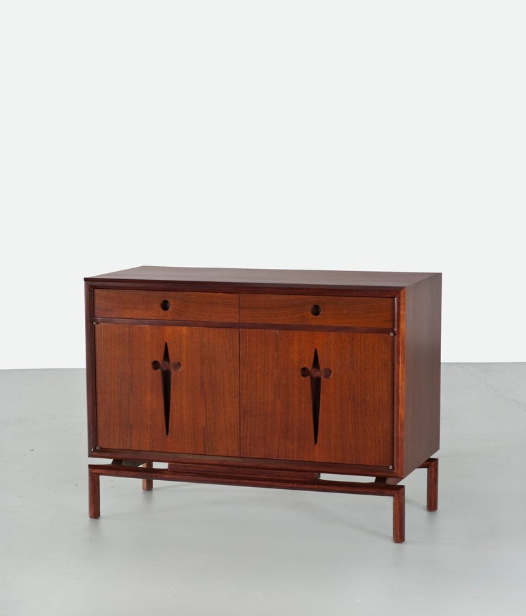A two-drawer walnut cabinet by Edmond Spence. The doors open to reveal three additional drawers and three fixed shelves.