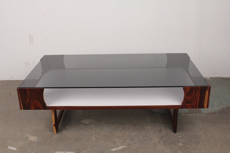 Newly produced solid rosewood coffee table with smoke glass top, copied from a Norwegian 70s piece produced by Bruksbo and designed by Torbjorn Afdal.

Made locally in Los Angeles of solid rosewood legs and frame, with laminate white shelf as