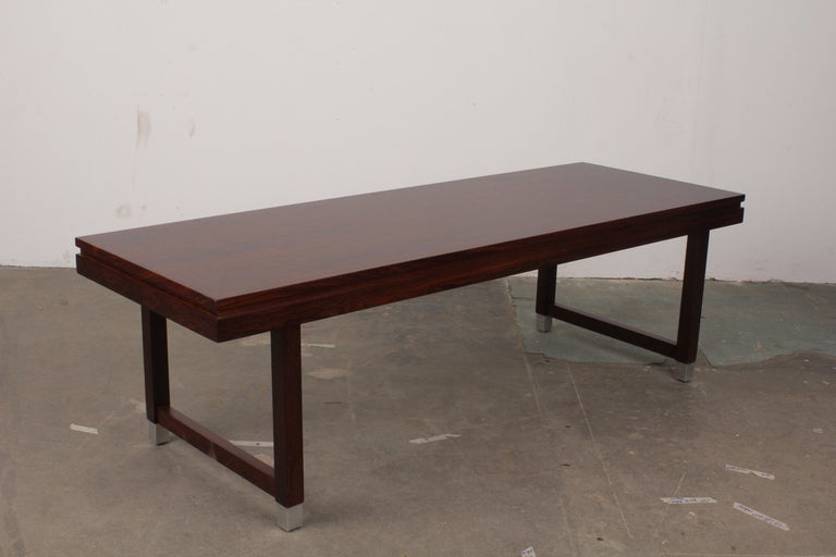 Beautifully restored to new condition is a rosewood coffee table by Kai Kristiansen. Aluminum footings add detail and elegance to this sleek and collectable coffee table.