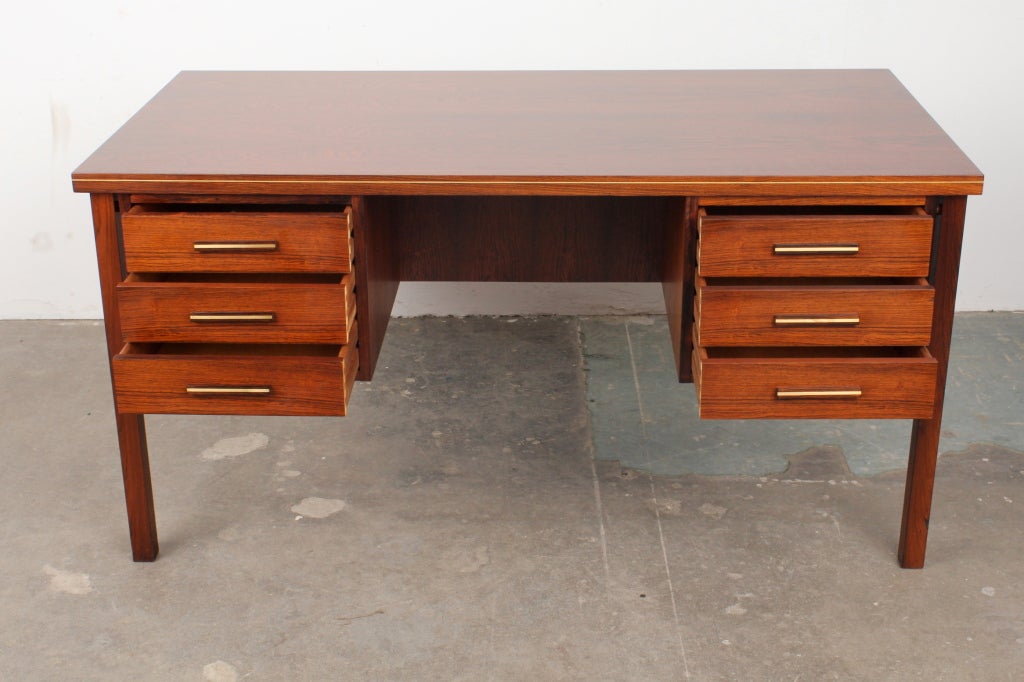 Beautifully restored rosewood mid century modern executive desk with brass hardware and brass inlay framing the desk top. This desk has drawers on one side and shelving and a pull down bar on the opposite side. A desk you and your clients can enjoy.