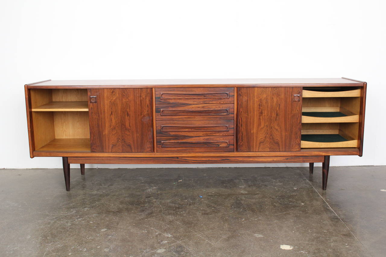 Mid Century Modern Danish Rosewood Sideboard  newly refinished in lacquer. This piece has two sliding doors on each side with four drawers in the center.  Beautiful book matched grain on the rosewood door fronts.