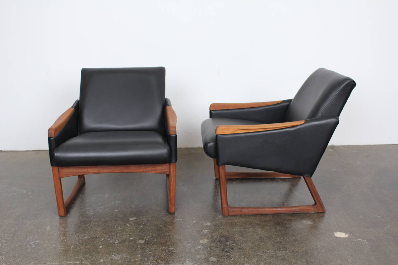 A pair of lovely Mid-Century lounge chairs on sculptural sled bases, complete with teak arm inserts. The swept angle of the bases add a touch of flair to an already attractive set.