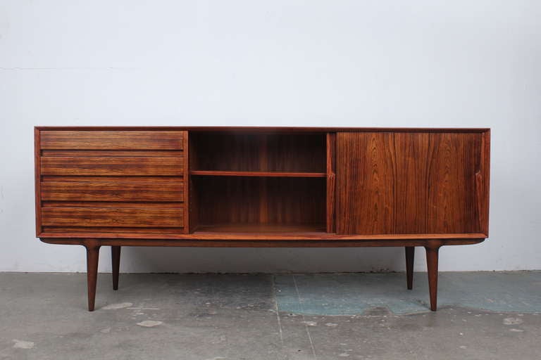Very rare low rosewood model 18 sideboard by Gunni Omann for Omann Jun Mobelfabrik.  This is a sleek and handsome sideboard that sits on Omann's signature sculptural legs.  Four drawers to the left of two sliding doors that open to a large storage