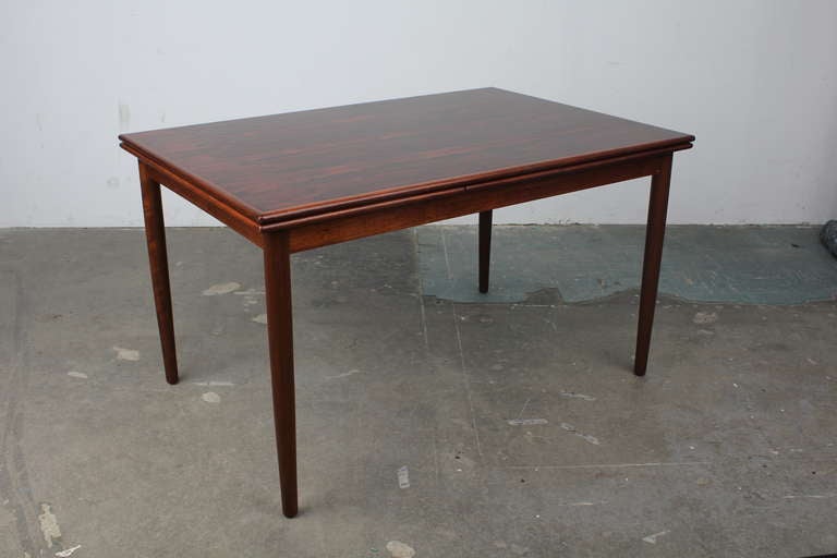 Newly refinished vintage rosewood mid century modern dining table with two pull out draw leafs. A spectacular grain pattern and large surface area make this a perfect table for entertaining.