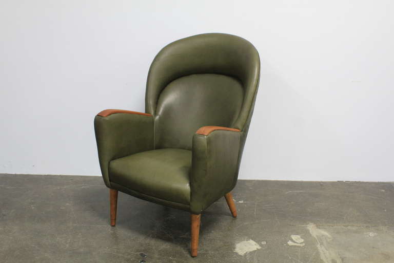 Tall back Danish mid century modern lounge chair with curved/scalloped back, teak inset arms and 4 oak tapering legs.  Newly upholstered in green leather with a tight back and seat style.
