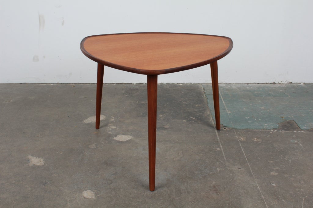 Triangular shaped, raised lip teak coffee table from Denmark, 1960's.  Raised lip edge band is stained darker to contrast with the teak table top.