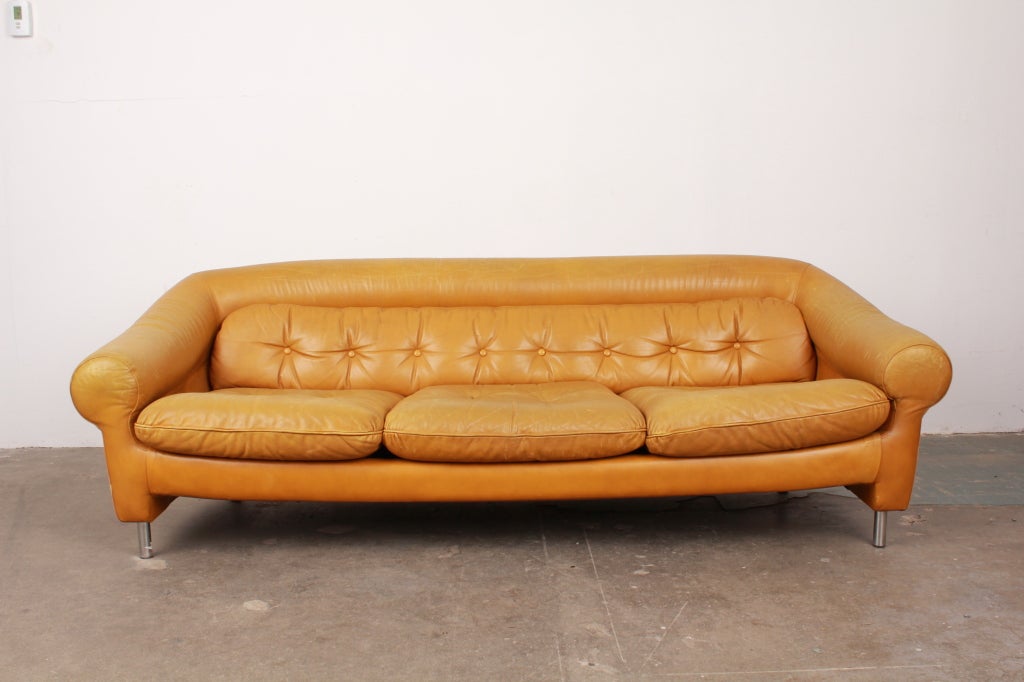 Danish mid century modern three seat leather sofa with loose seat cushions, tufted single back cushion, with curved back and arms. Excellent patina on original leather, with metal legs.  (Matching pair of chairs available).