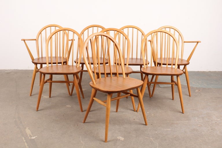 Solid elm dining table with 2 leaves, made by Ercol of England.  Set includes 8 chairs, 2 of which are captains chairs. Table is solid wood as are the dining chairs.  Newly refinished in lacquer and in excellent condition.