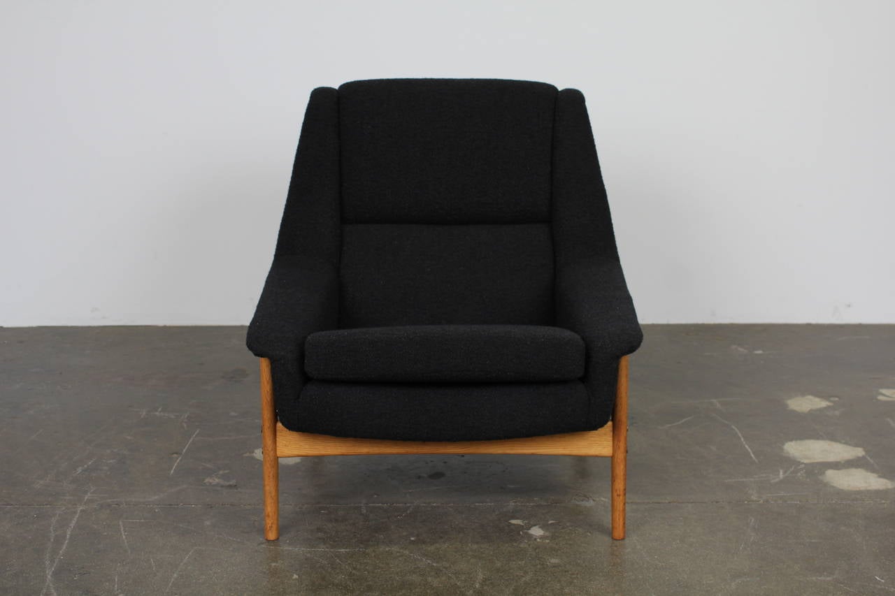 Swedish Mid-Century Modern tall lounge chair, newly upholstered in black bouclé fabric with oak legs. Designed by Folke Ohlsson for DUX.