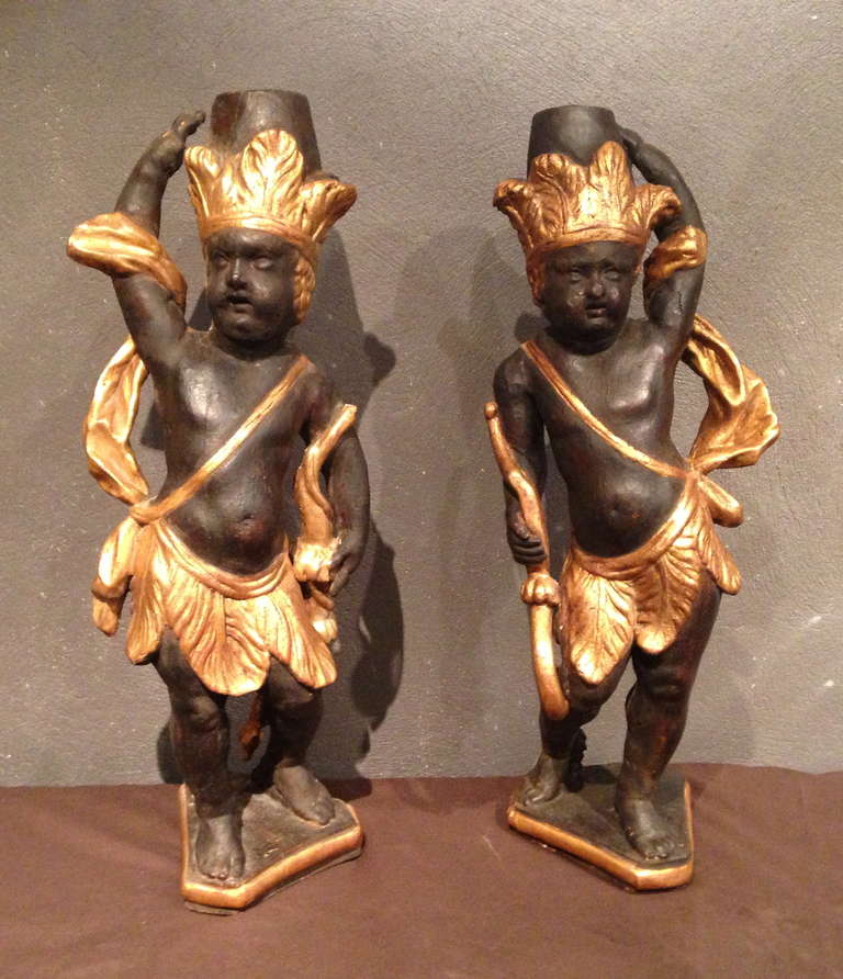 Pair of candelabra, black and gold lacquered oak representing Indian wearing a loincloth and a feather headdress and holding a bow. 
These Indian symbolize America. 
Paris, Louis XIV period circa 1700. 

The theme of the American Indian was very