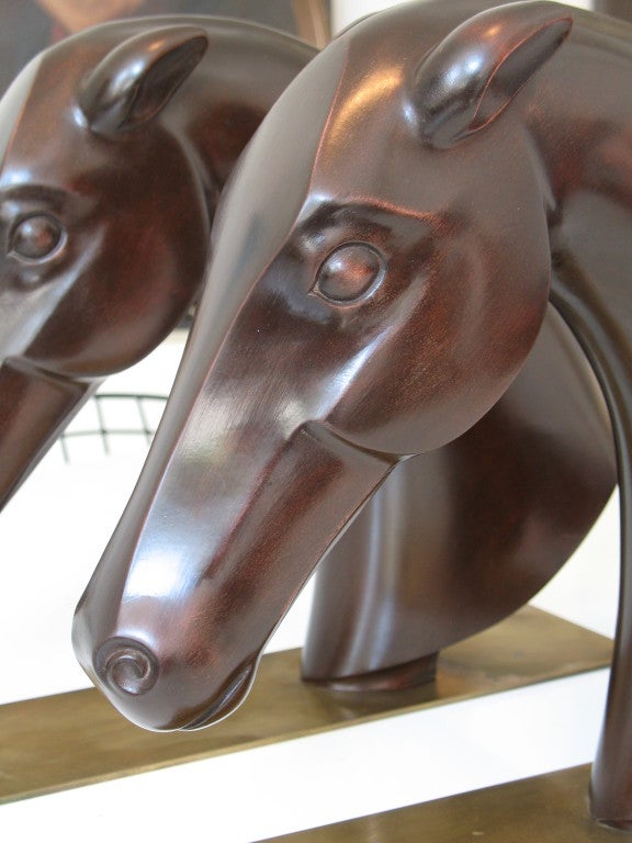 A substantial pair of carved stylised Horses Heads by Hagenauer of Austria. Sculpted in well figured timber and mounted on rectangular brass bases, the underside of which bear the makers stamps.