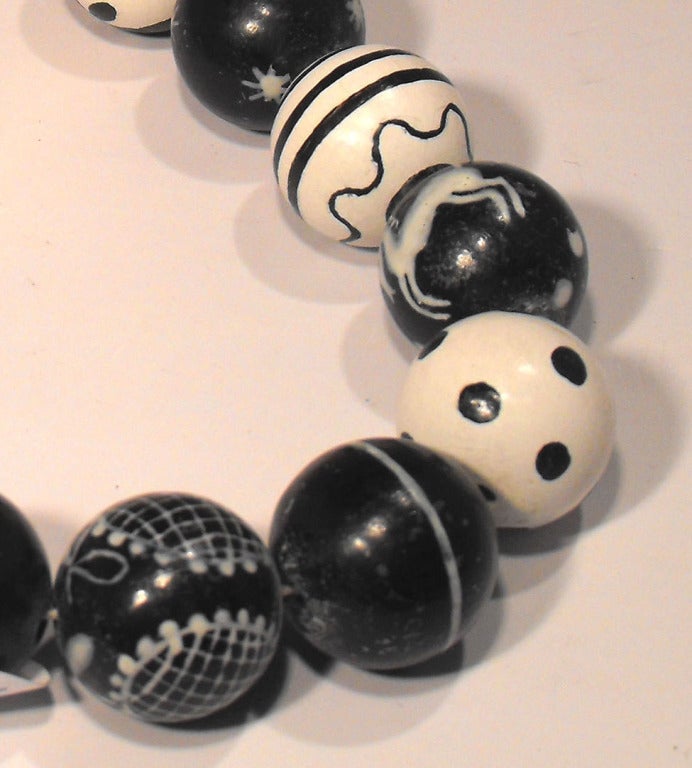 A Wiener Werkstatte necklace consisting of wooden spherical beads all hand painted with varying black and white geometric patterns.
