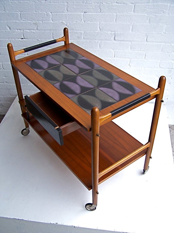 Danish teak tea cart with abstract tile top. Beautiful colours, very well made piece.


Sizes: 77,5cm length, 42cm width, 56cm height