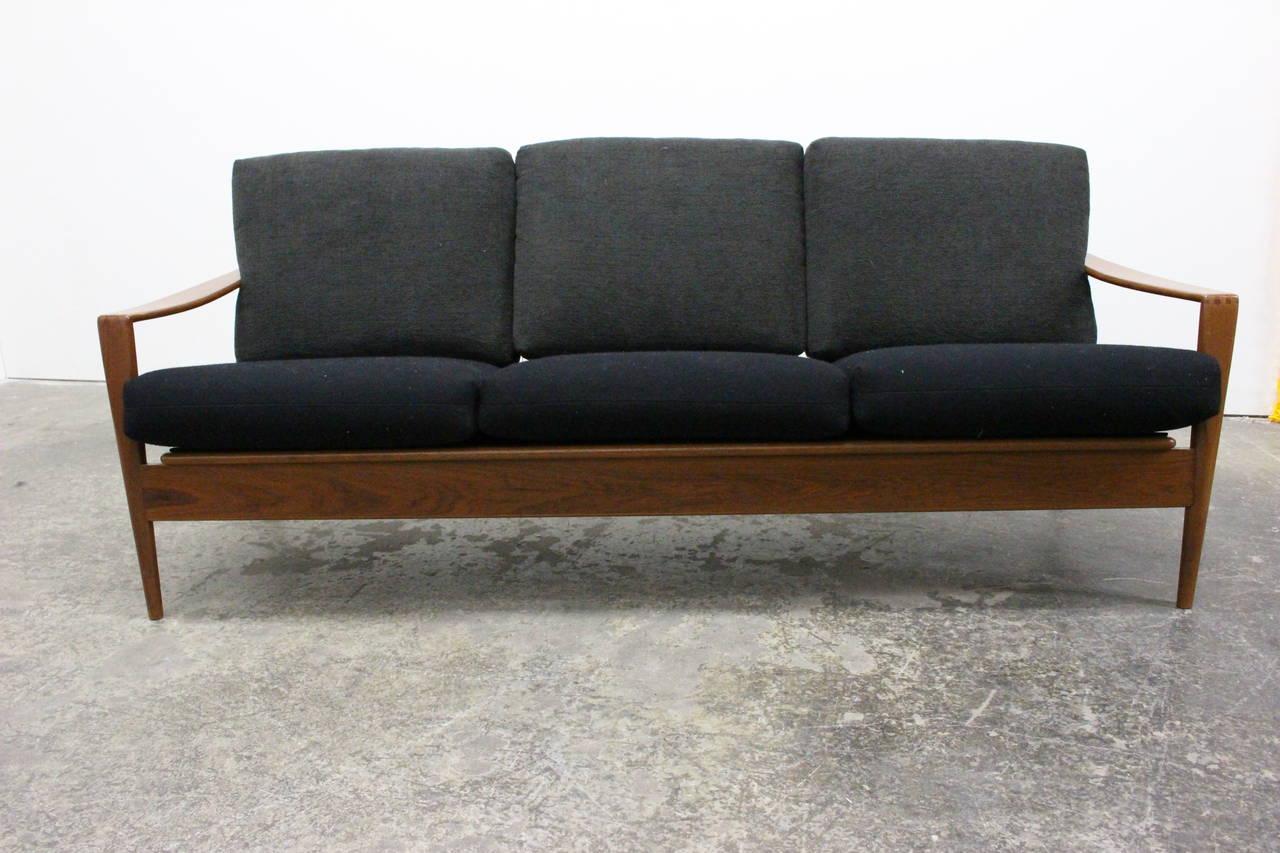 Wood framed sofa by Illum Wikkelso. Sofa has three (3) seat cushions in black and three (3) back cushions in dark gray. Finger joint construction around arm area. 

Dimensions: 71