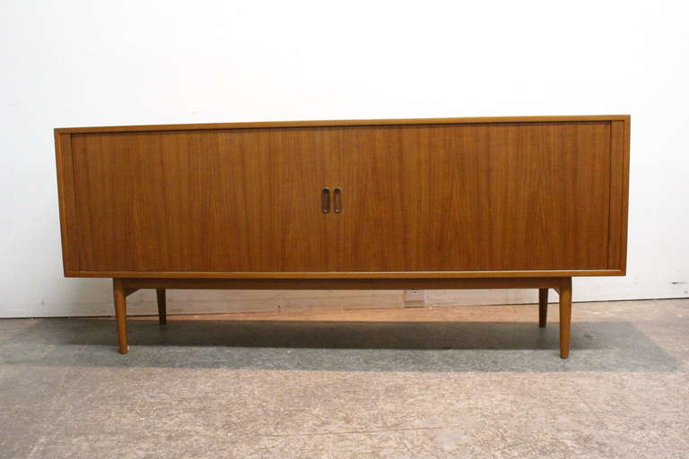 Stunning teak sideboard with tambour doors that roll into the backside of the piece. Interior with the characteristic Arne Vodder drawers and 3 shelves.