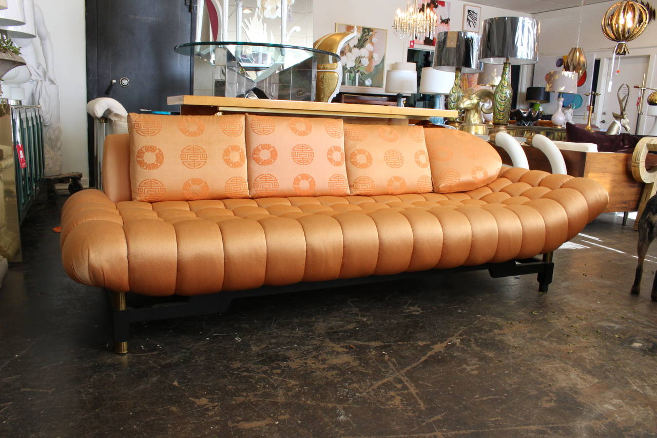 Hollywood Regency tufted sofa/daybed covered in original pink silk. Left side of sofa is slightly elevated. Asian influenced with brass accents, circa 1950s.

Dimensions: 90
