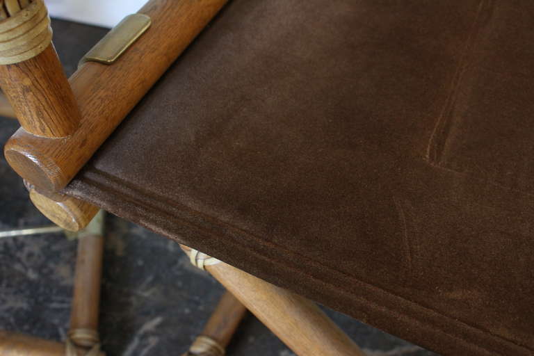 A pair directors chairs by McGuire covered in brown suede, all original and in great shape. Solid oak frames with brass stretchers at the base of each chair. These chairs bear original McGuire tags.