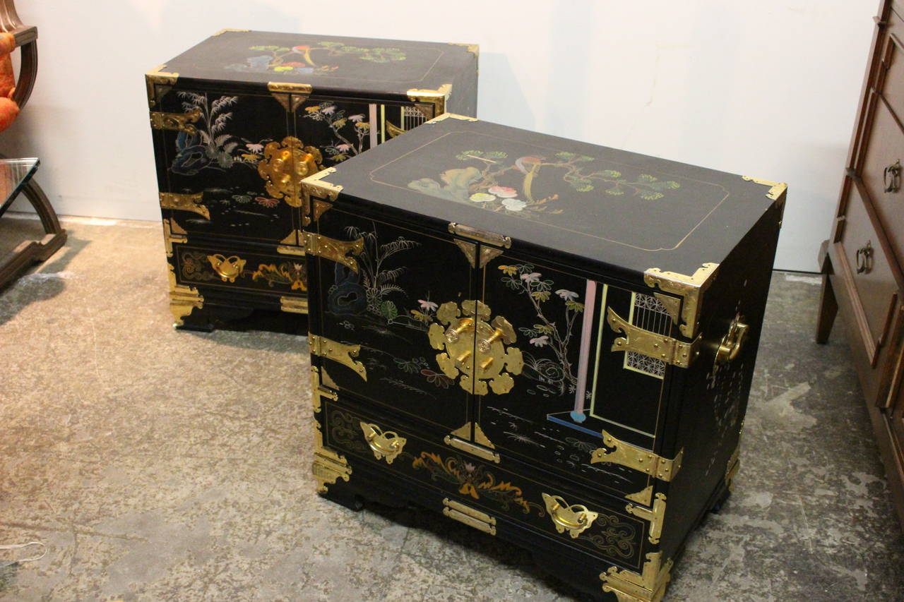 Pair of Asian nightstands with brass accents. Hand-painted scenes adorn the exterior of chest.

Dimensions: 24