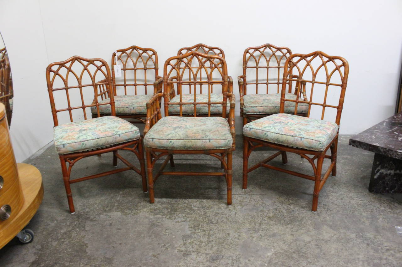 Set of six (6) McGuire dining chairs. Rattan chairs with leather strapping and cushion seating. There are four arm and two armless chairs, circa 1960s.

Dimensions: 23